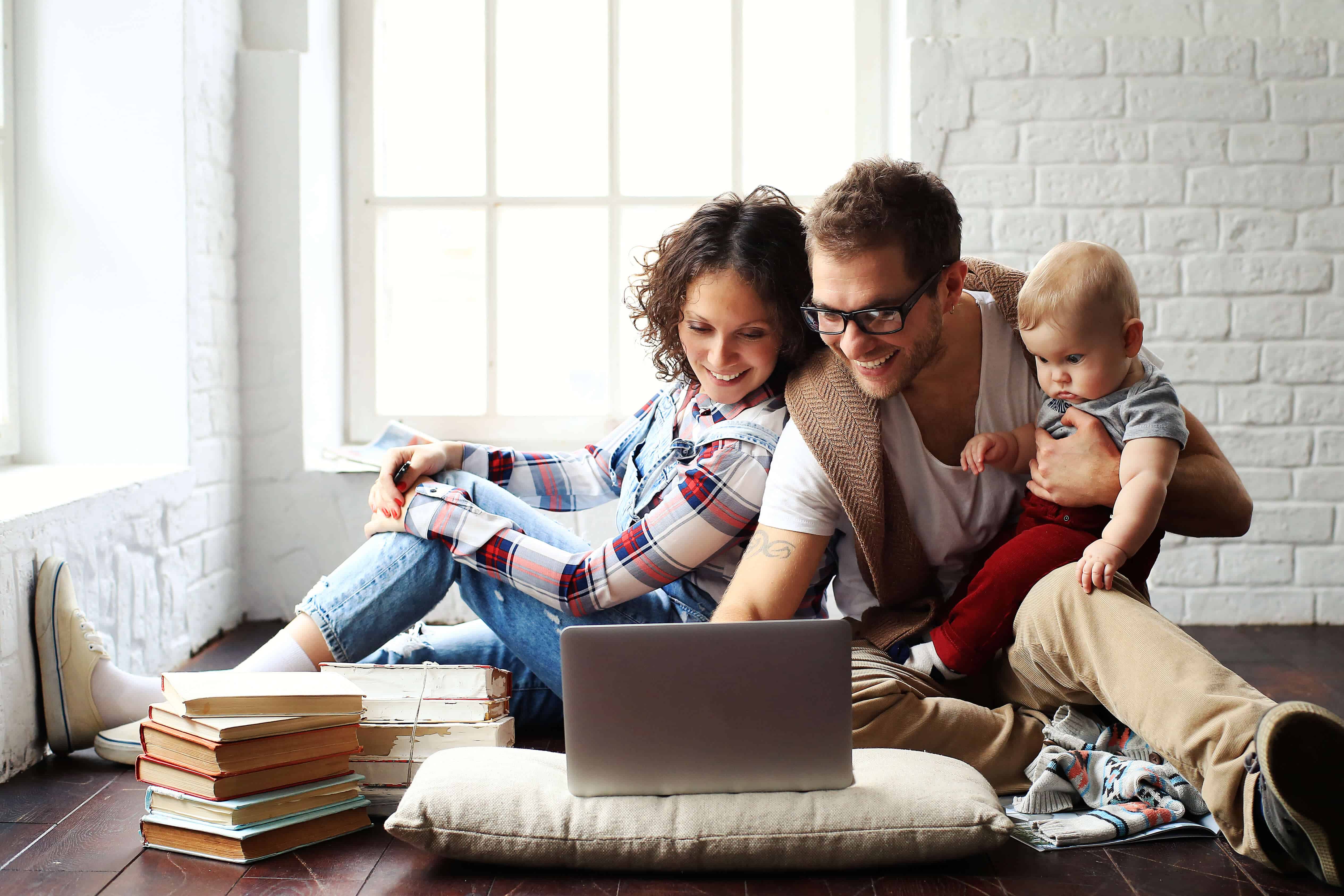 Jong gezin gelukkig in nieuwe woning op de laptop finzie website