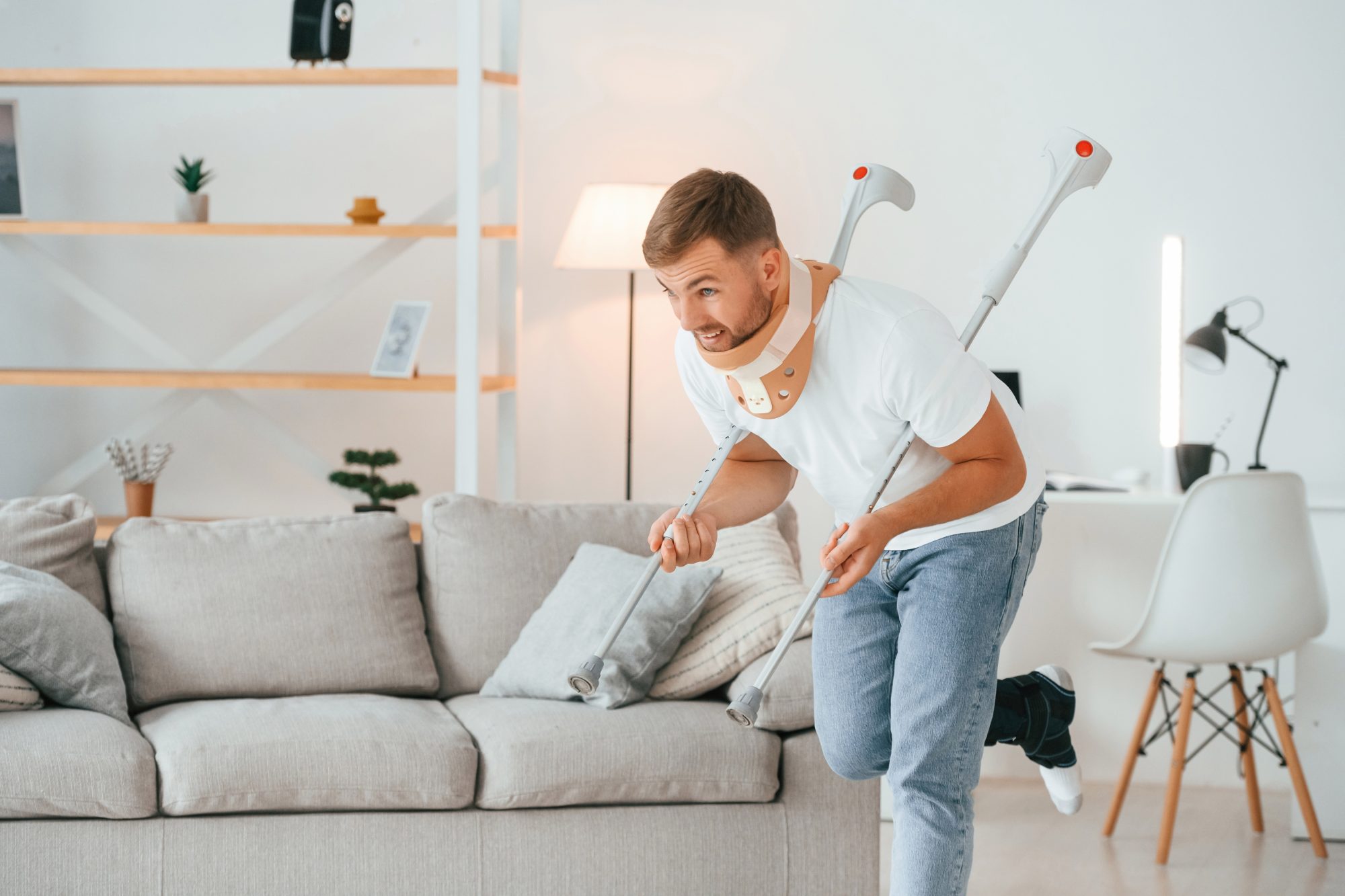 Man met nekkraag en krukken in woonkamer – illustratie waarom wintersportdekking en annuleringsverzekering nuttig zijn