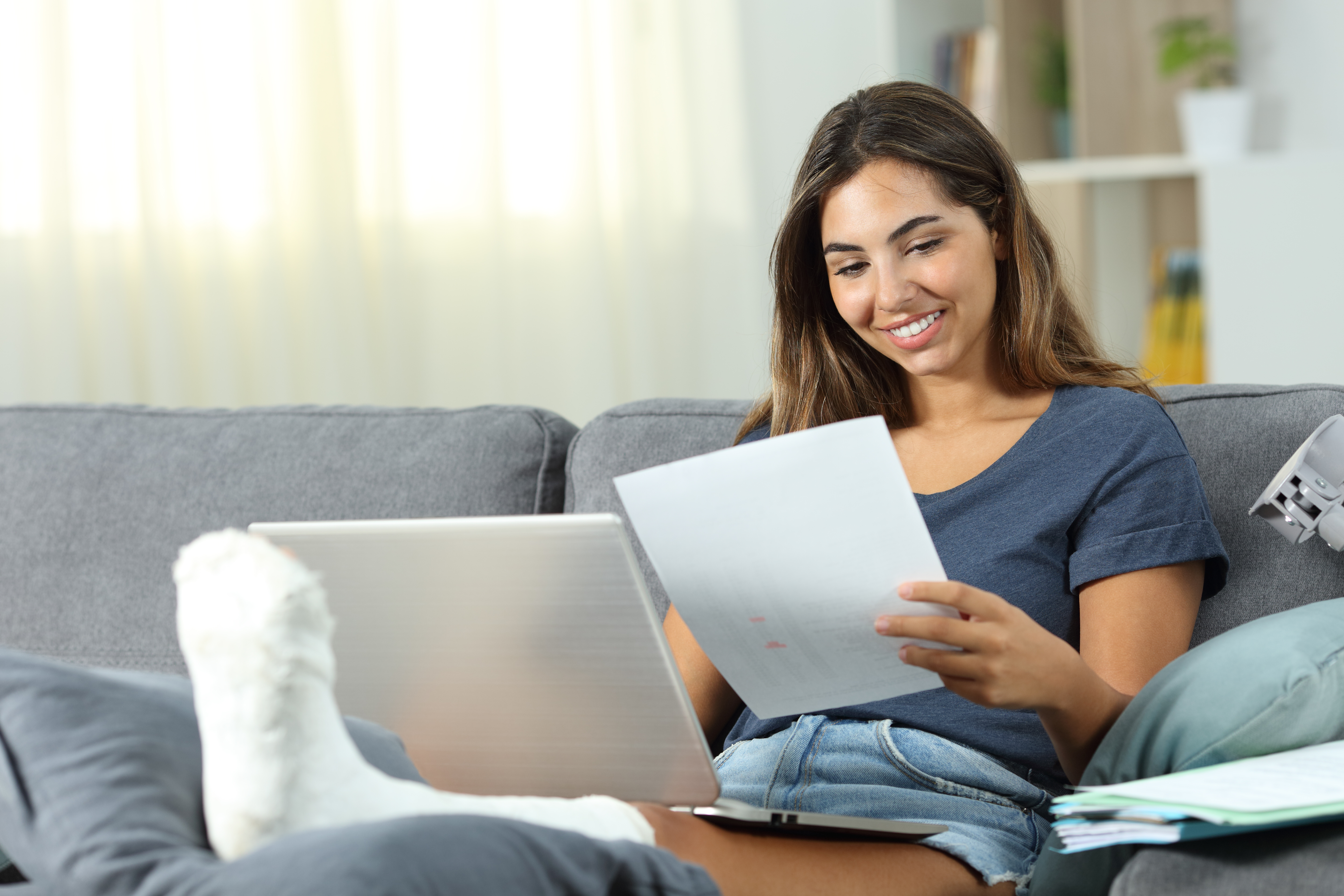 Vrouw vergelijkt zorgverzekering 2026 op laptop en papier; thuis op de bank, focus op premie en overstappen