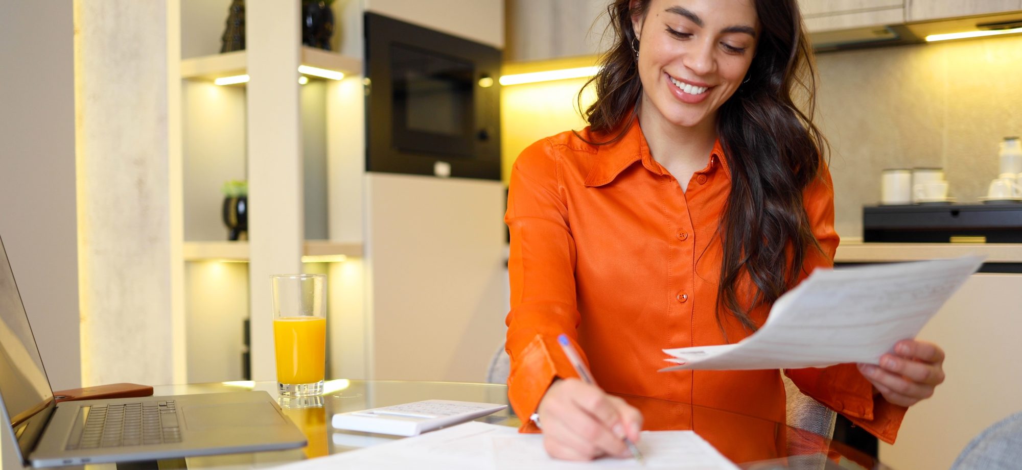 Vrouw bekijkt haar financiële administratie voor 2026 aan de keukentafel.