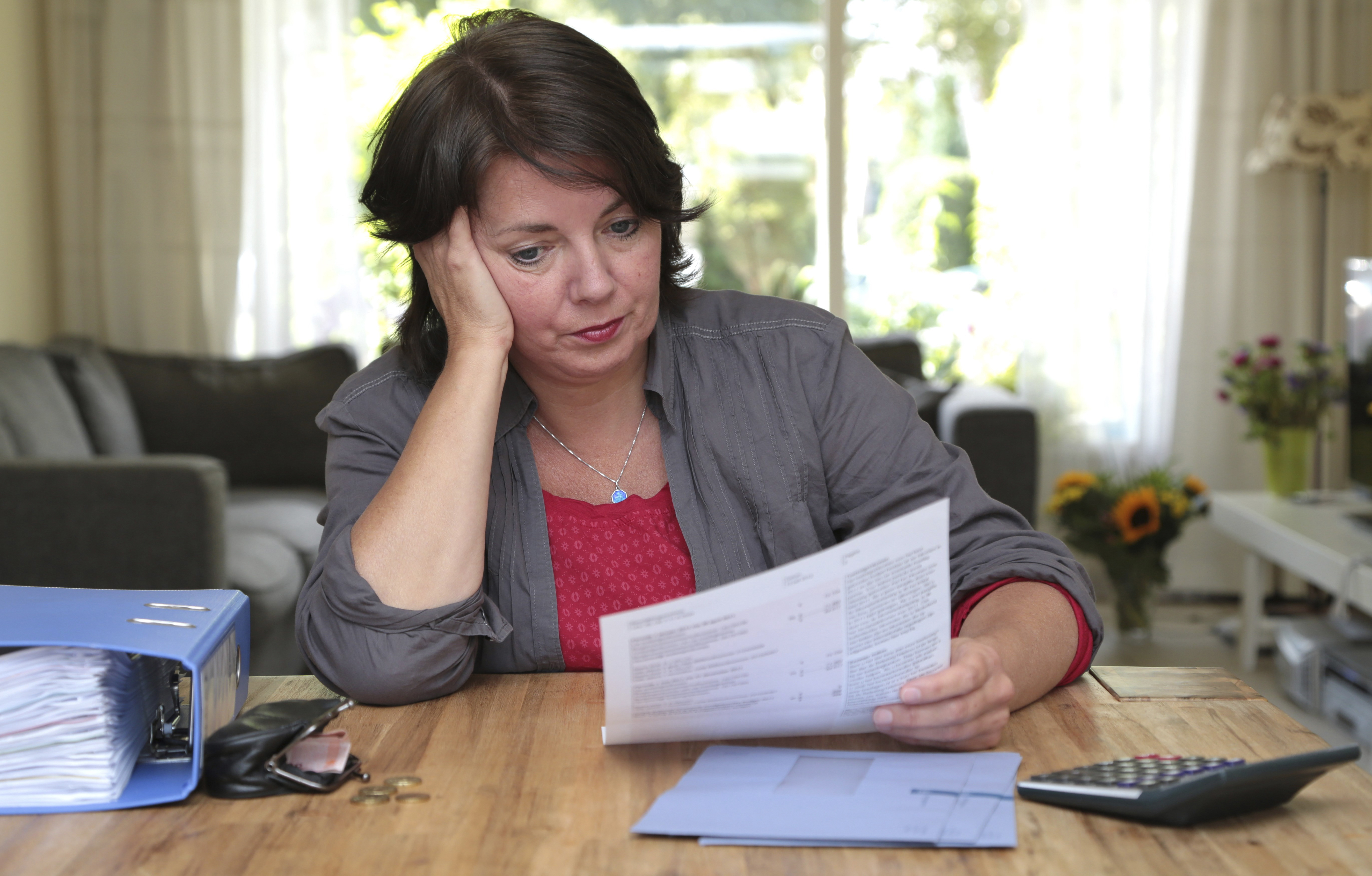 Vrouw bekijkt thuis haar belastingpapieren en rekent haar financiële situatie door