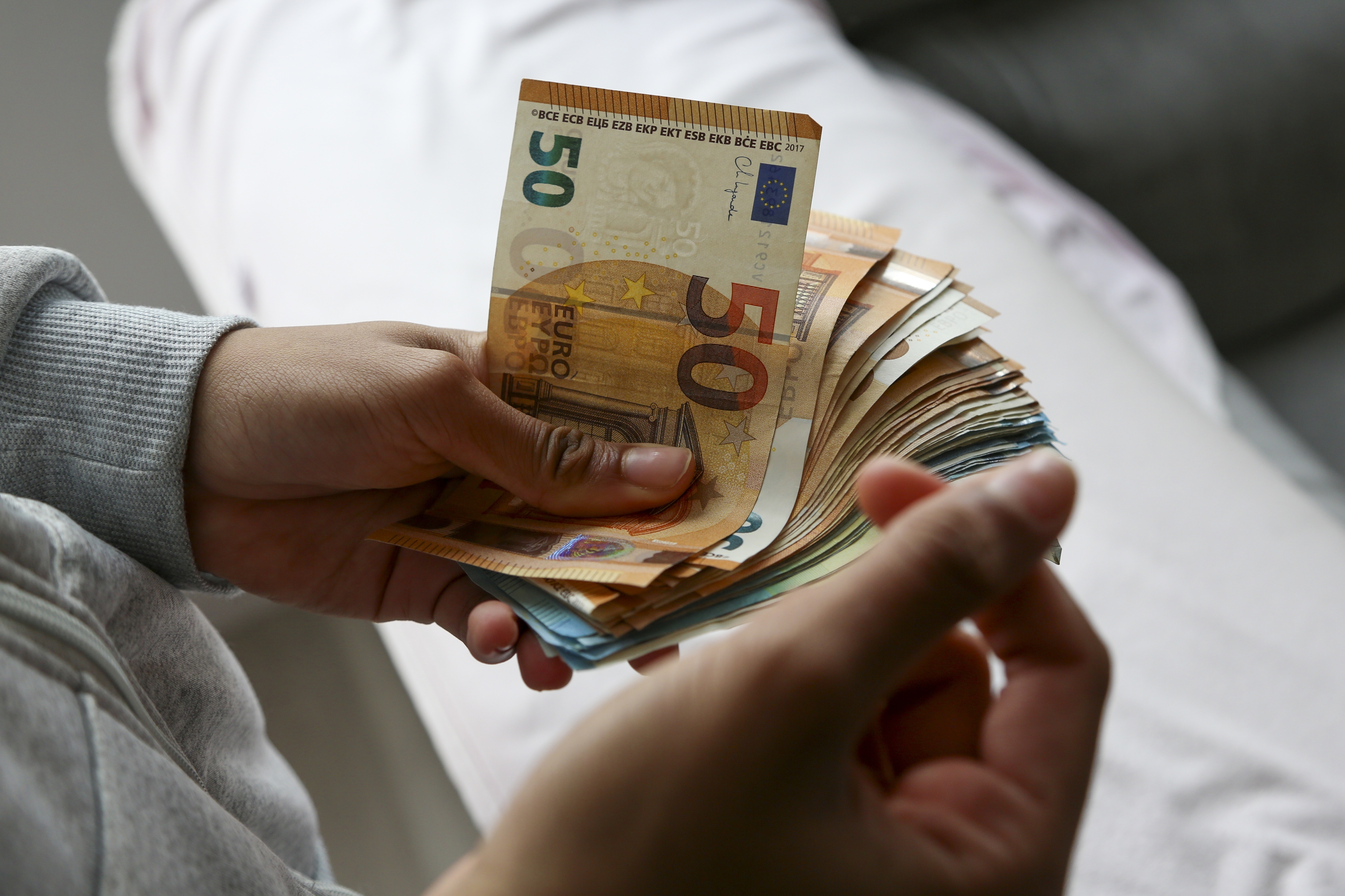 Persoon telt eurobiljetten als beeld bij elke maand 200 euro beleggen