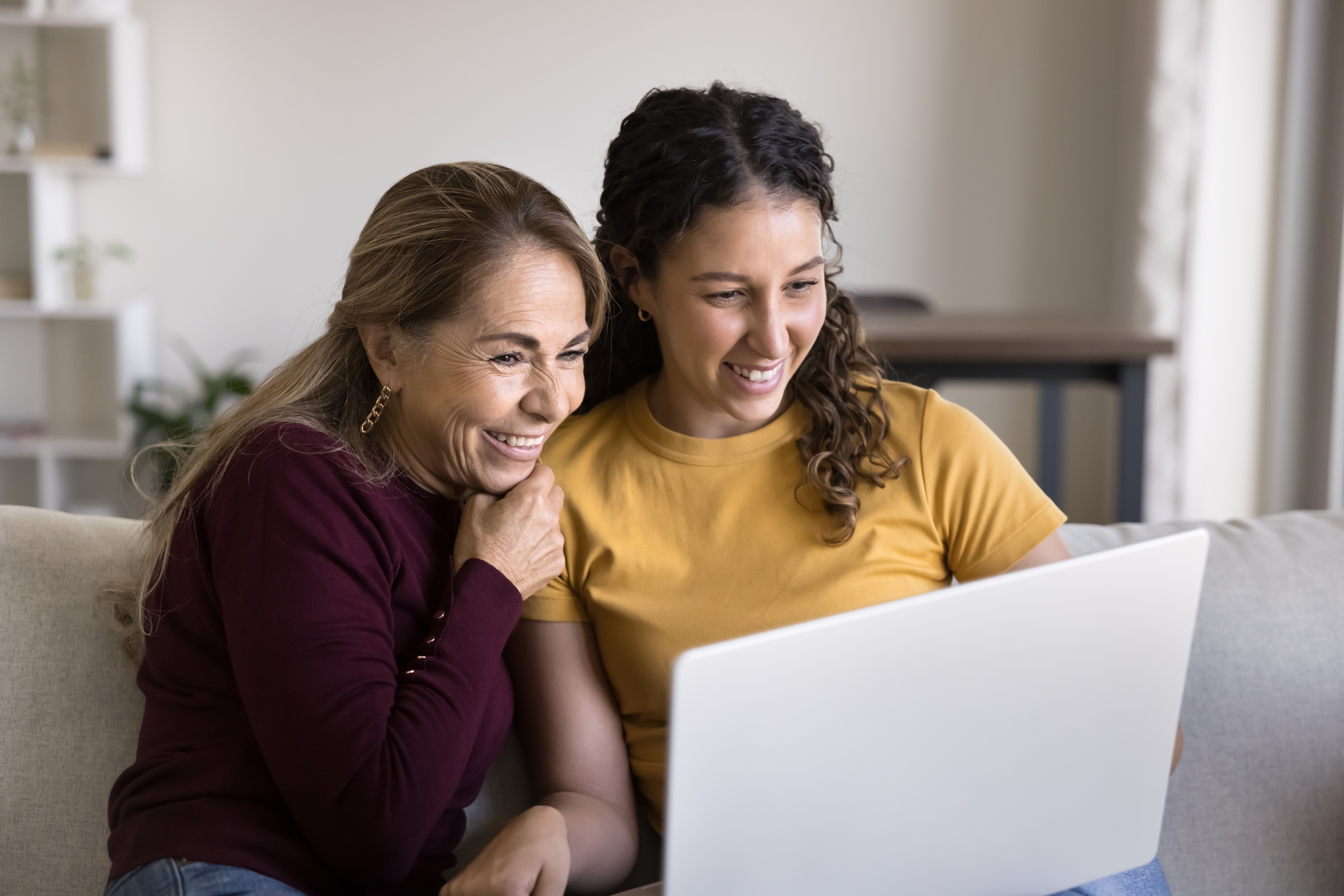Moeder en volwassen dochter kijken samen op een laptop naar de mogelijkheden voor het kopen van een woning.
